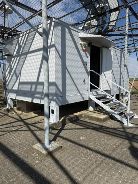 Technikcontainer mit Stahltreppe unter einer Stahlgitterkonstruktion